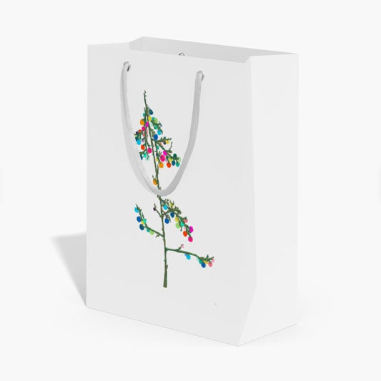 A white paper gift bag with white handles, featuring a printed graphic of a green branch decorated with colorful Christmas lights, set against a plain white background.